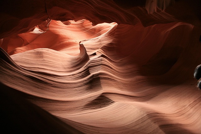 Rainbow arching over Landscape Arch in Arches National Park with snow patches and desert vegetation in the foreground.