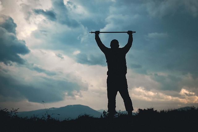 Close-up of a muddy Jeep Wrangler parked on a rocky overlook near Moab, Utah, with golden desert light and two people watching the sunset.
