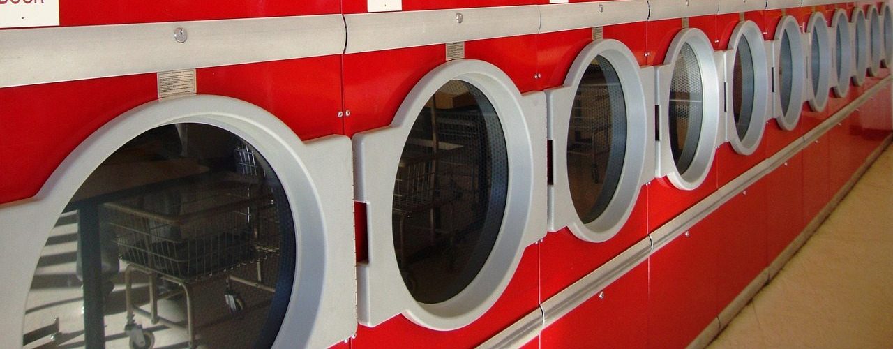 Row of bright red dryers inside a Moab laundromat with socks hanging on a clothesline above the machines.