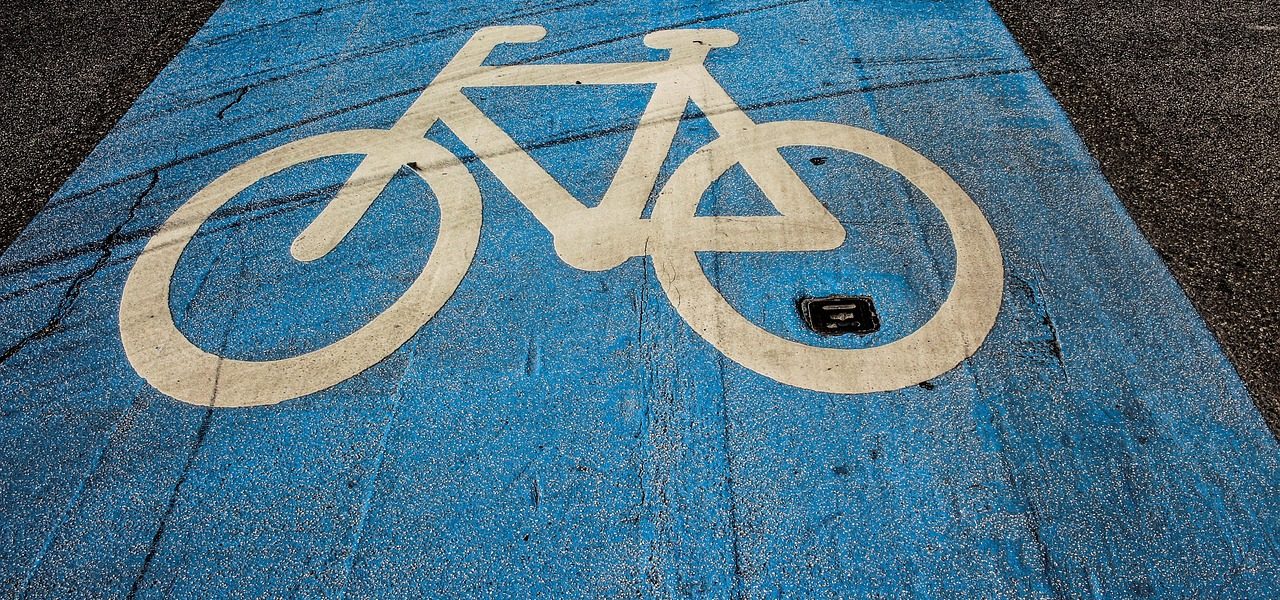 Close-up view of a blue bike lane with a white bicycle symbol painted on the pavement, representing a designated cycling path.