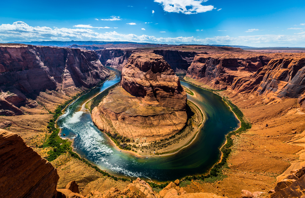 An aerial view of Horseshoe Bend shows the Colorado River curving sharply around a massive sandstone butte.