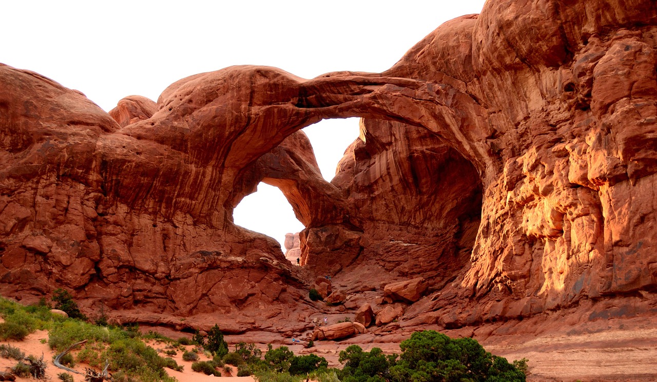 Double Arch in Arches National Park. The opening of both sandstone arches is visible with hikers underneath.